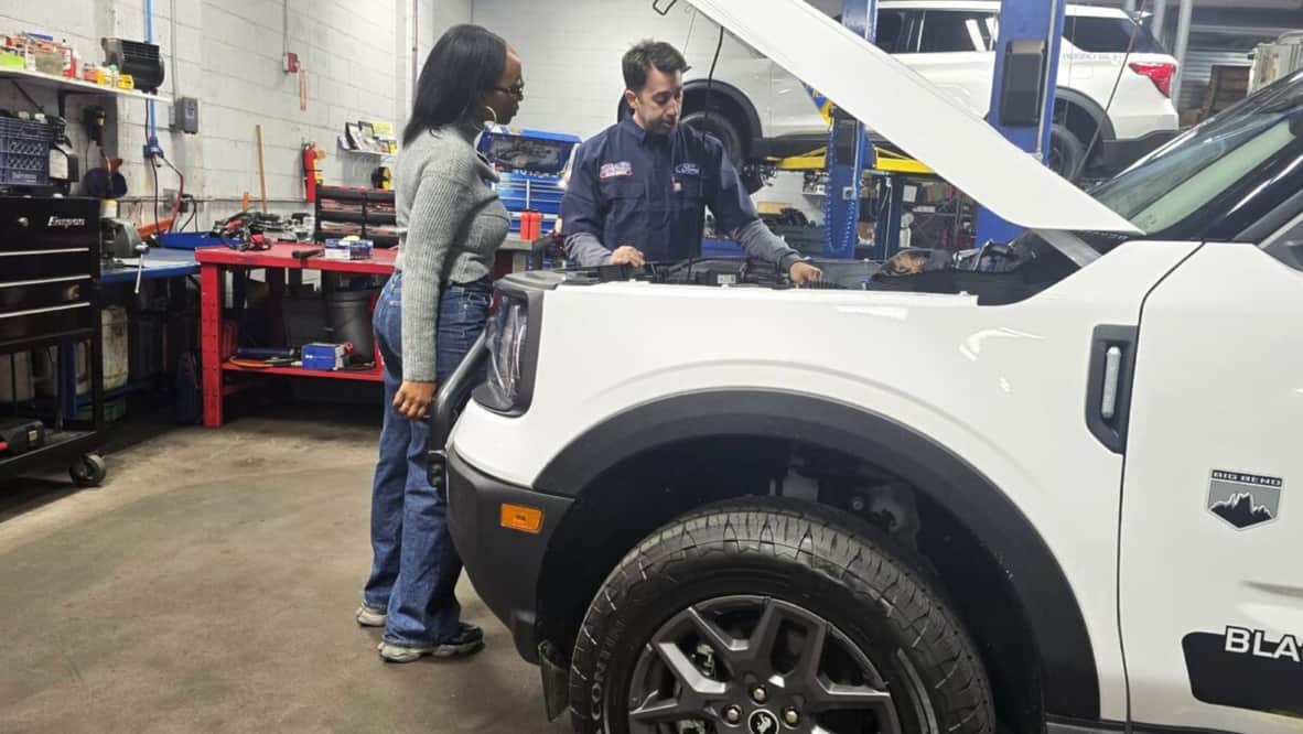 Kim Standing Over The Engine Of A Ford Bronco Sport With A Dealership Technician